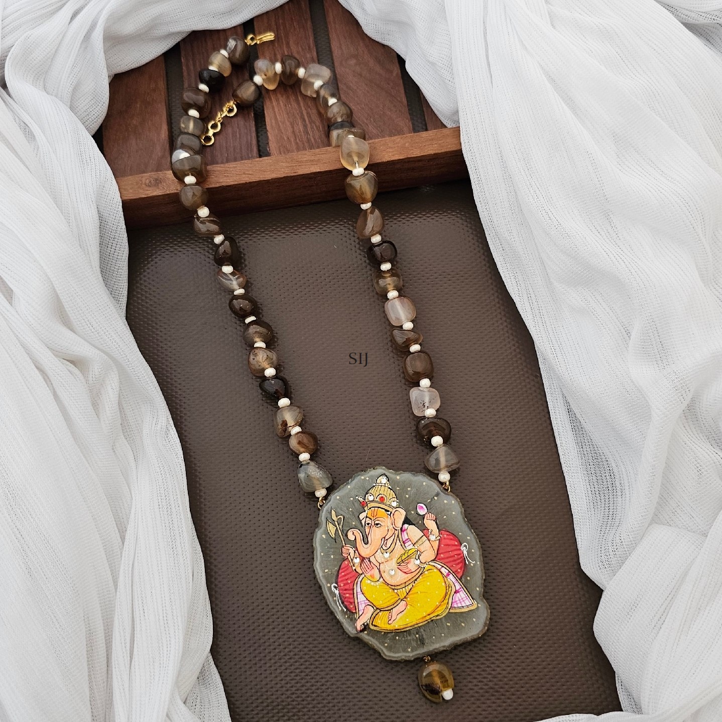 The Ganesh pendant, revered in Hinduism, adorns this necklace alongside brown and white beads. Symbolizing wisdom and remover of obstacles, Ganesh brings blessings. Crafted with care, this pendant necklace exudes spiritual significance and aesthetic charm. Wear it with reverence or as a fashion statement, carrying the essence of divine protection.